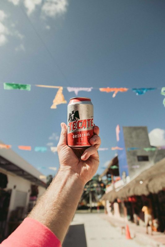person holding Tecate Original can