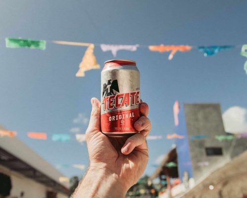 person holding Tecate Original can